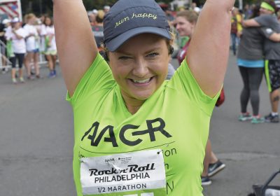 Sarah Happy cheerfully crosses the finish line at the 2017 AACR Rock ’n’ Roll Half Marathon.