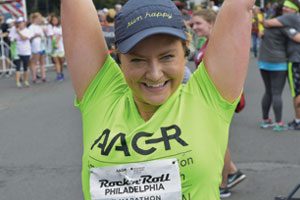 Sarah Happy cheerfully crosses  the finish line at the 2017 AACR Rock 'n' Roll Half Marathon.