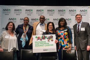 AACR President Dr. Elizabeth M. Jaffee, holding the sign, stands with speakers at the AACR’s public forum, Progress and Promise Against Cancer, held in Rosemont, Illinois, in April.